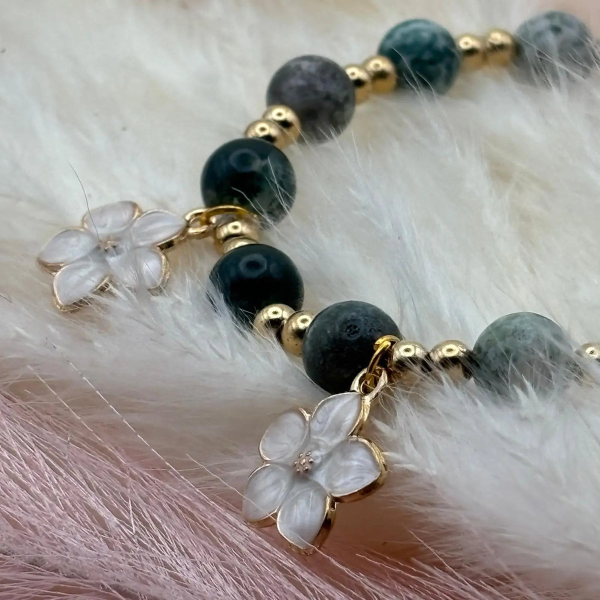 Vue de près d'un bracelet en perles artisanal avec breloques fleurs nacrées et perles naturelles vertes sur élastique 