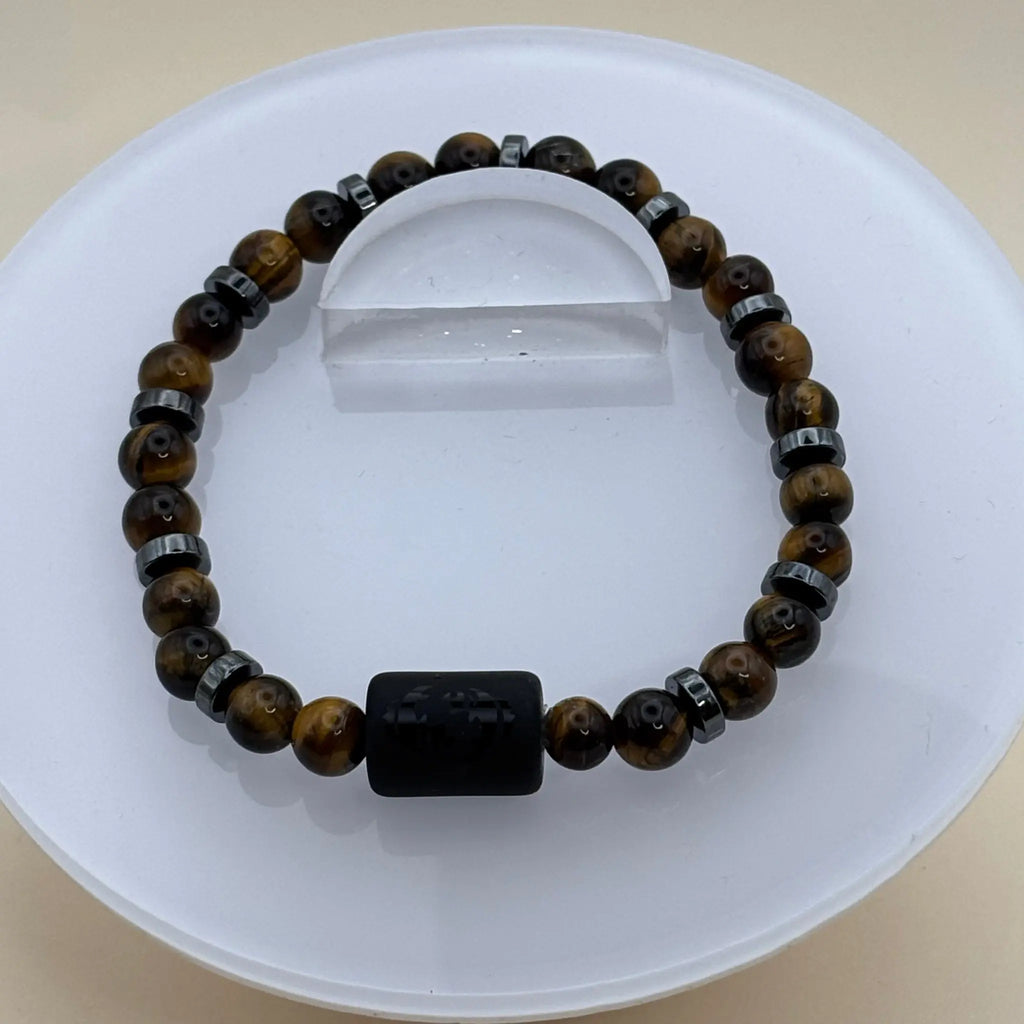 Bracelet aux perles marron doré et anneaux métalliques gris avec un cylindre noir gravé au centre