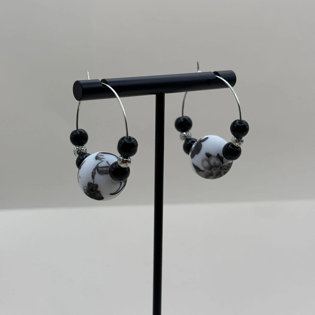 Boucles d'oreilles artisanales créole avec une perle fleurie et deux perles noires