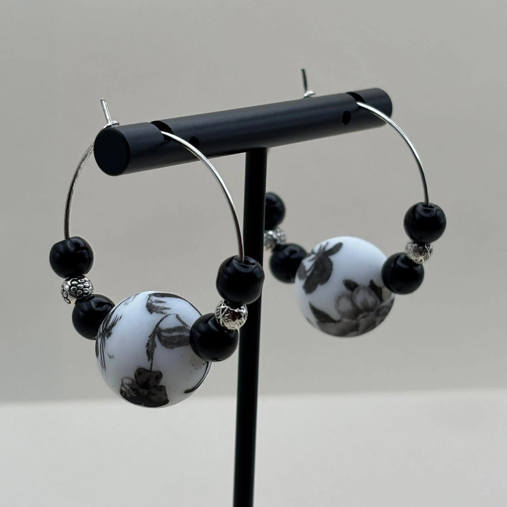 Boucles d'oreilles artisanales créole avec une perle fleurie et deux perles noires