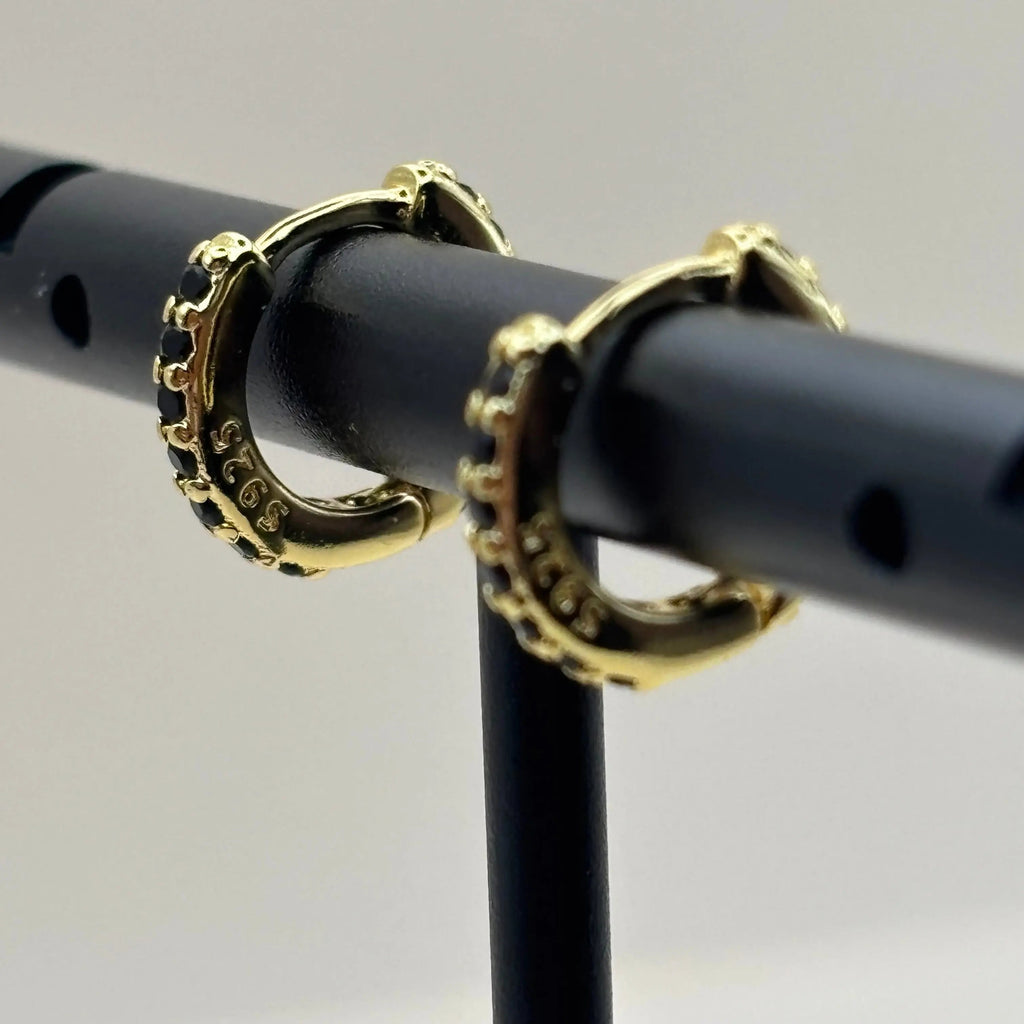 Un piercing de nez en plaqué or 18 carats, orné de zircons noirs.