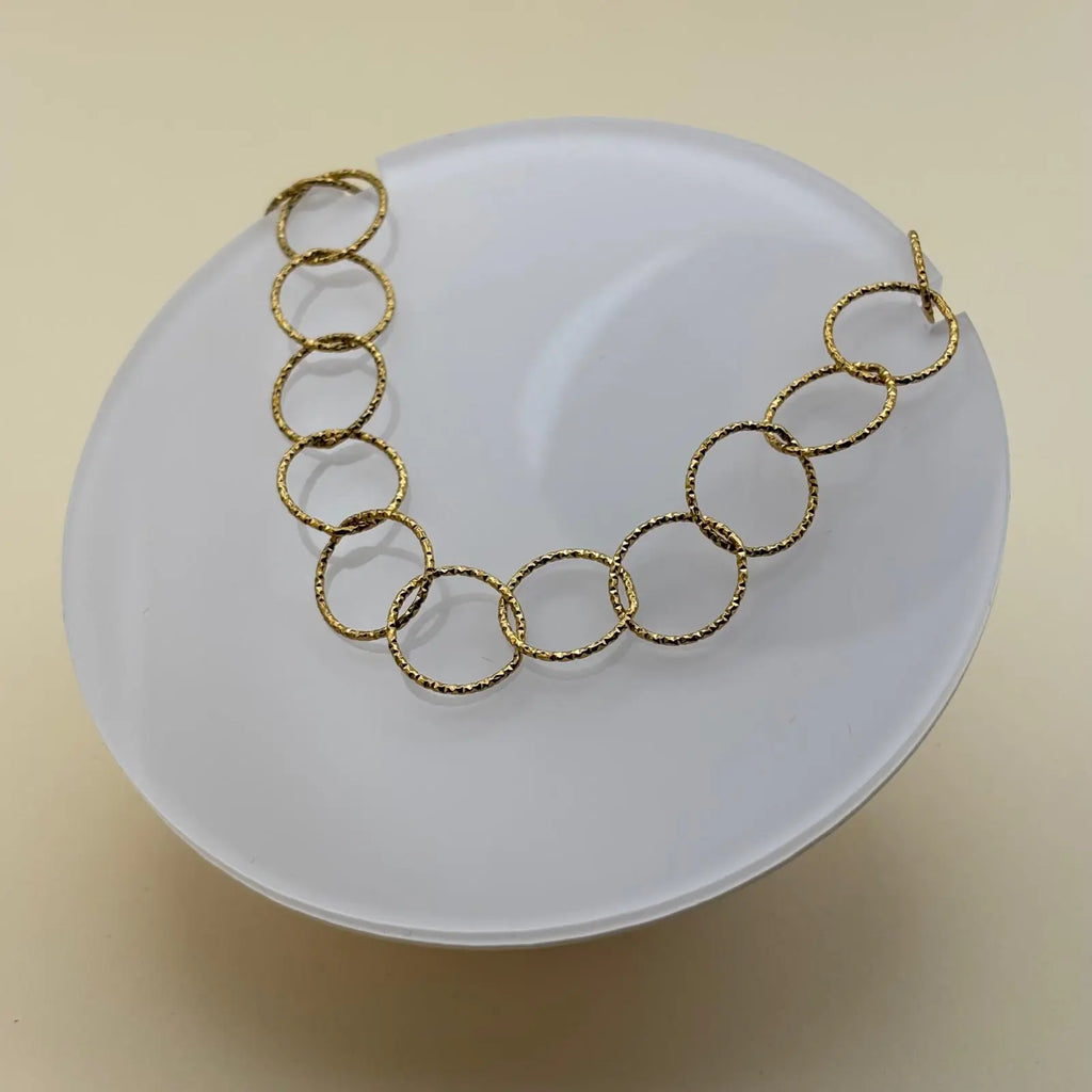 Bracelet de couleur dorée avec des anneaux dorés et médaillon avec un fermoir par barre