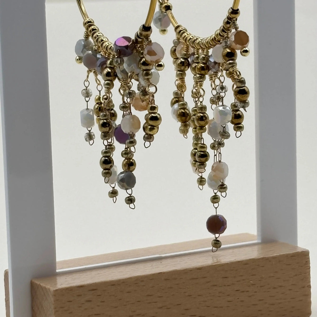 Une paire de boucles d'oreilles créoles dorées avec breloques perles de verre blanches en acier inoxydable