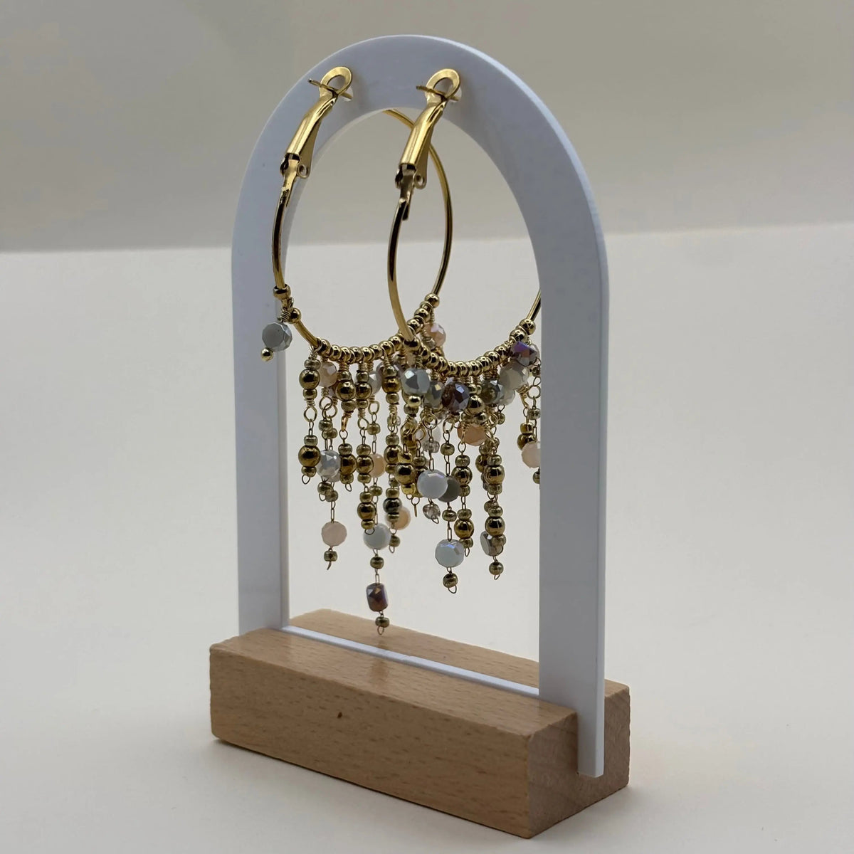 Des boucles d'oreilles créoles dorées avec breloques perles de verre blanches en acier inoxydable