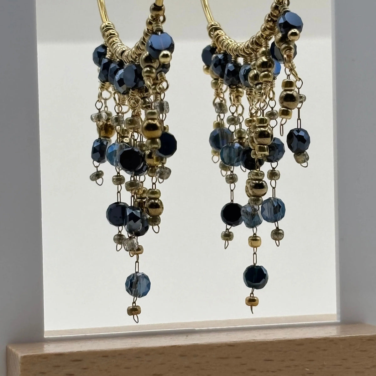 Des boucles d'oreilles créoles dorées avec breloques perles de verre bleues en acier inoxydable