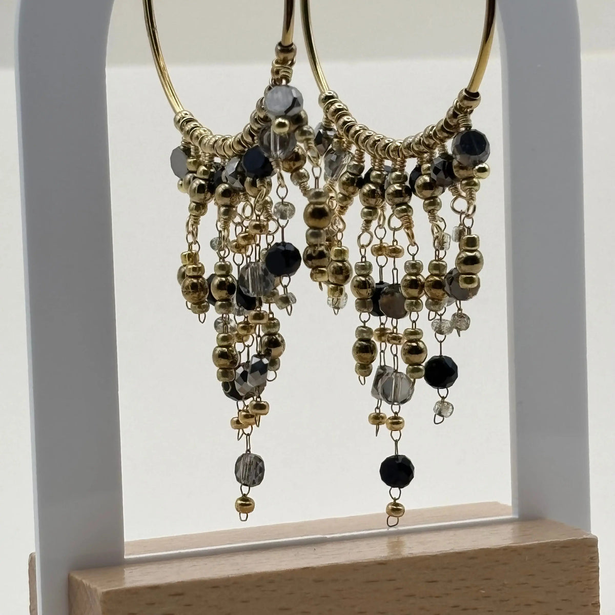 Une paire de boucles d'oreilles créoles dorées avec breloques perles de verre noires en acier inoxydable