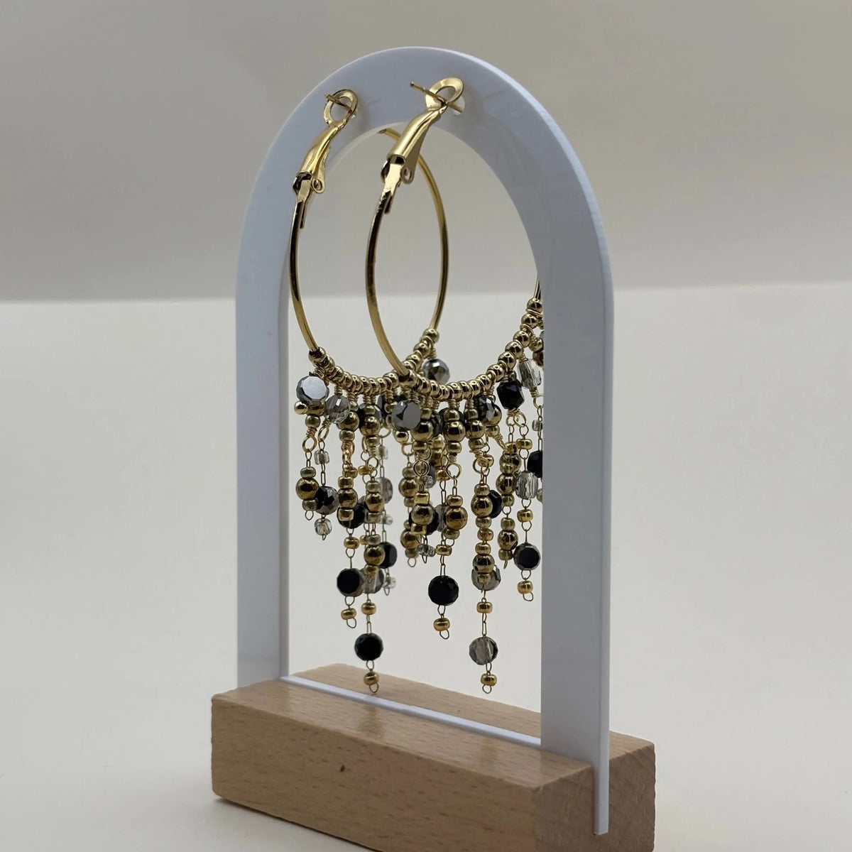 Des boucles d'oreilles créoles dorées avec breloques perles de verre noires en acier inoxydable