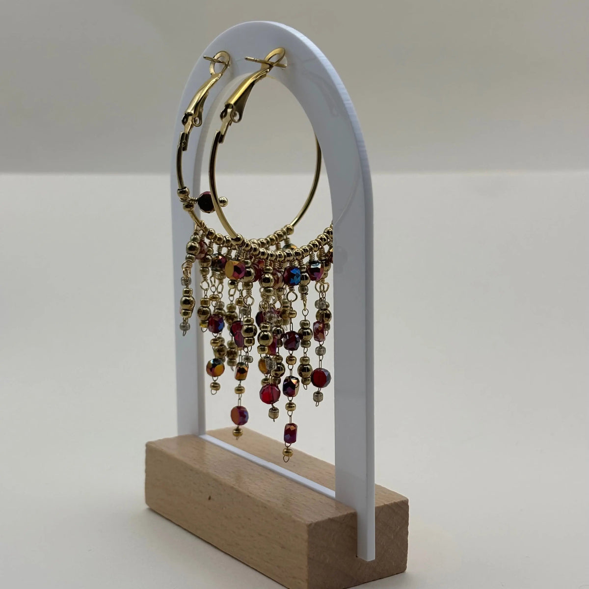 Une paire de boucles d'oreilles créoles dorées avec breloques perles de verre rouges en acier inoxydable