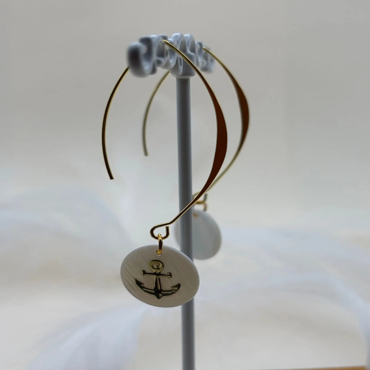 Une paire de boucles d'oreilles pendentif avec une pastille nacrée et dessin d'une ancre de marine