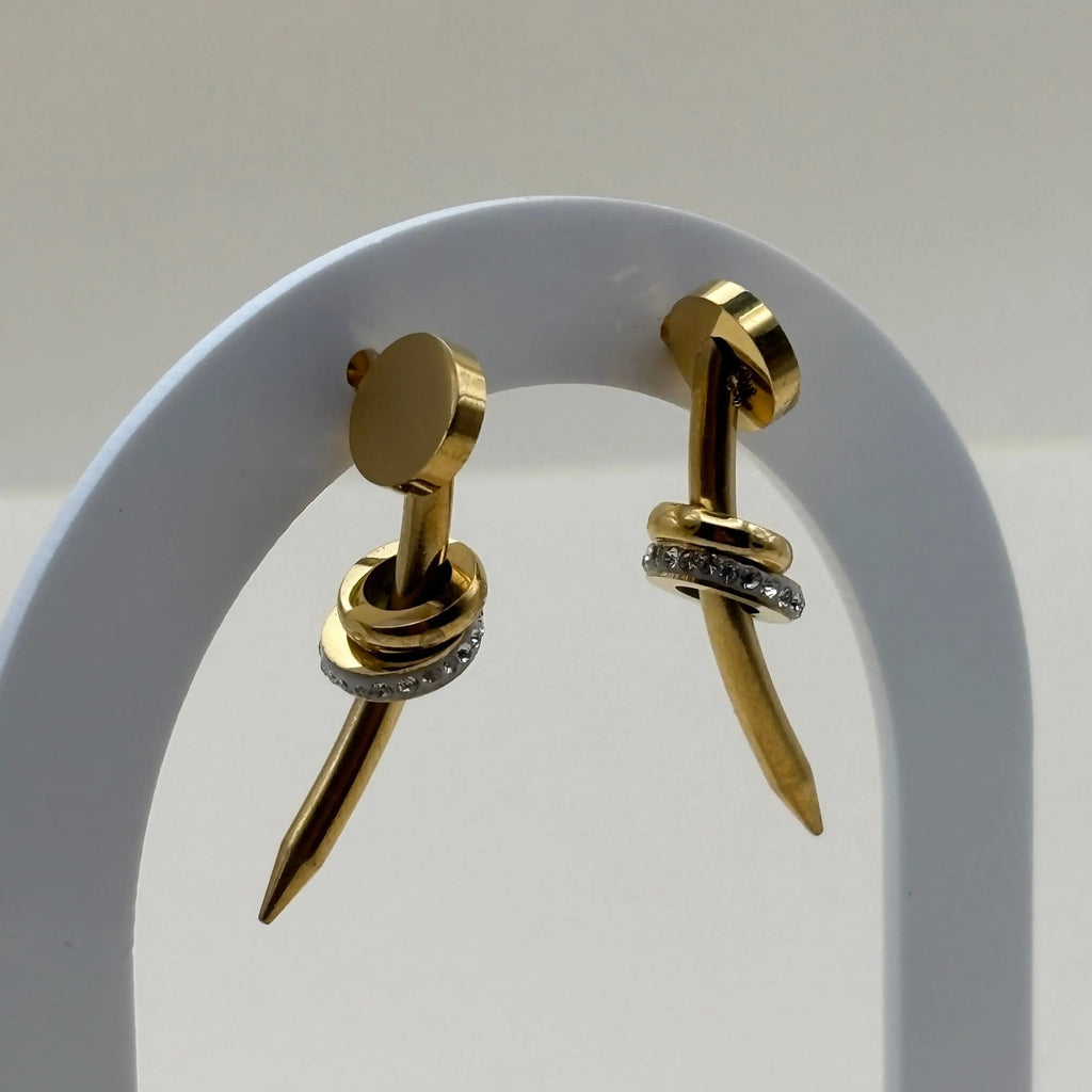Des boucles d'oreilles dorées avec motif clou et strass en acier inoxydable 