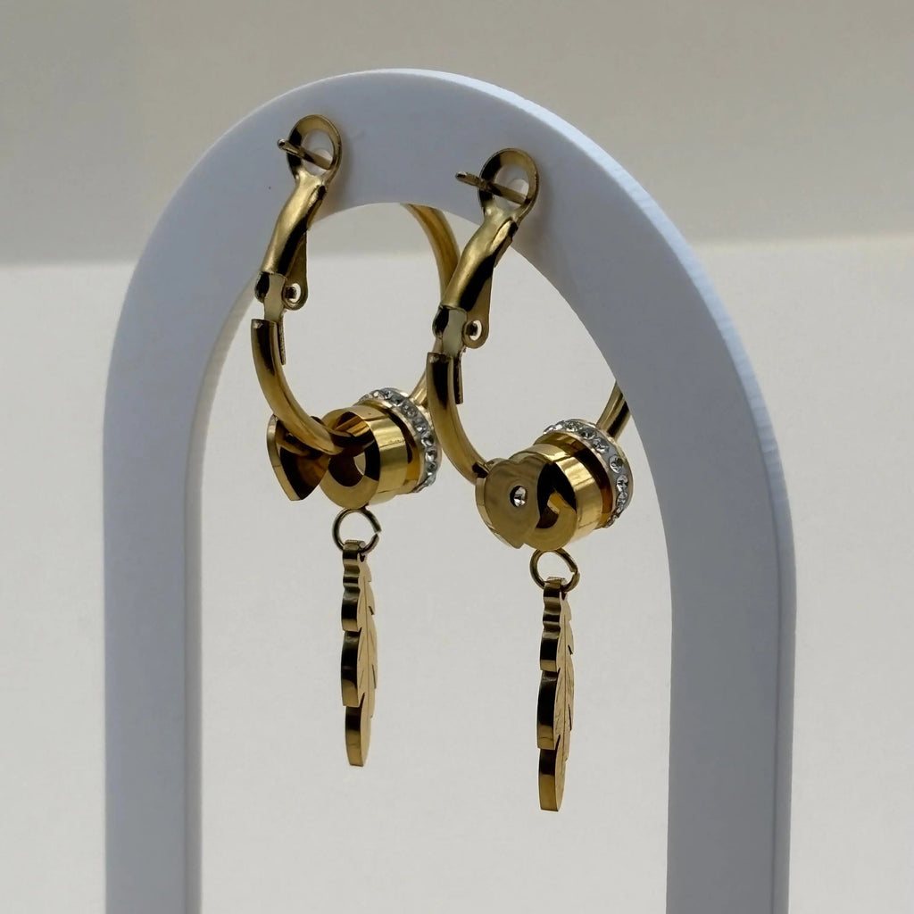 Une paire de boucles d'oreilles créoles dorées avec motif plume et strass argent en acier inoxydable 