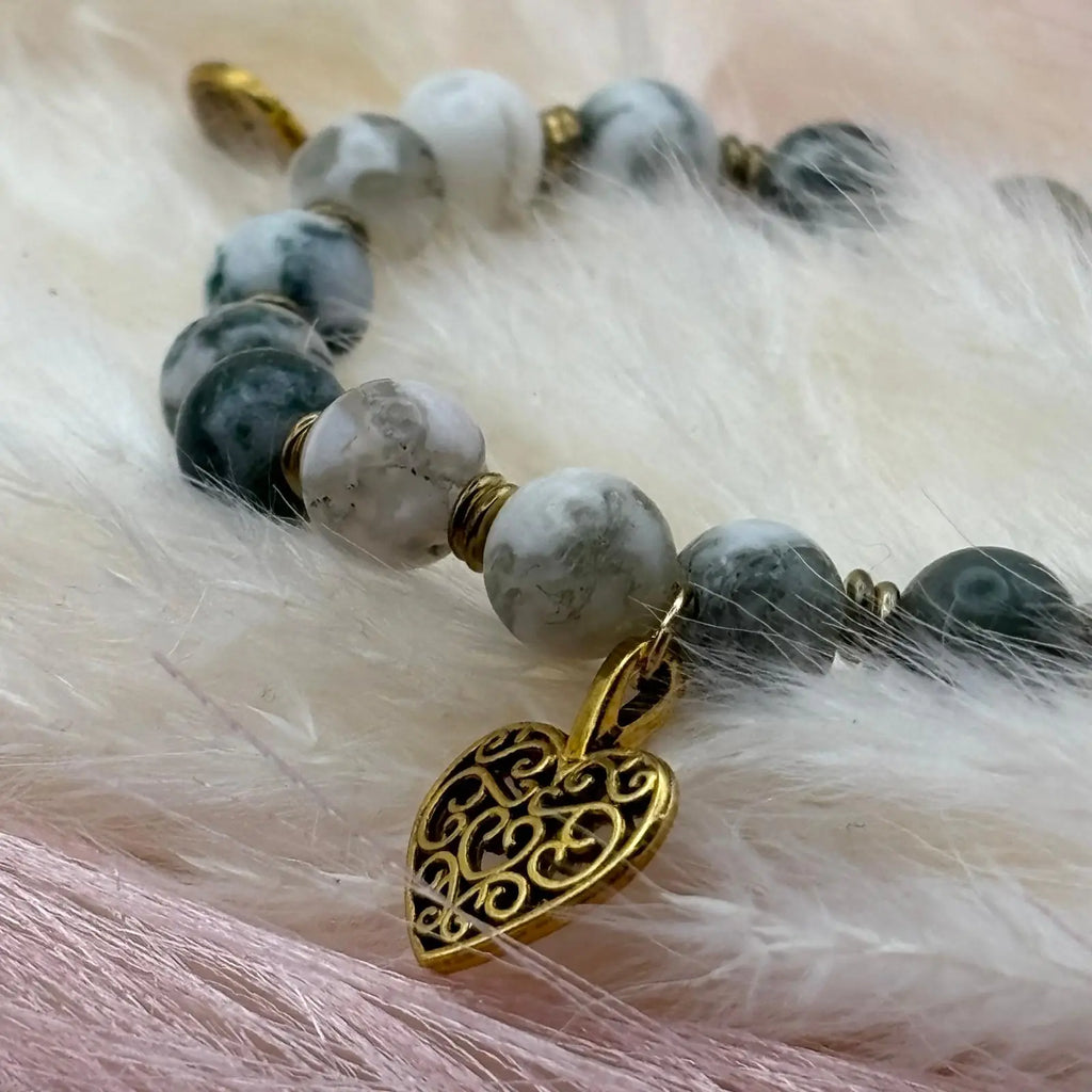 Vue de près d'un bracelet en perles artisanal avec breloques cœurs dorés et perles naturelles marbrées vertes sur élastique 