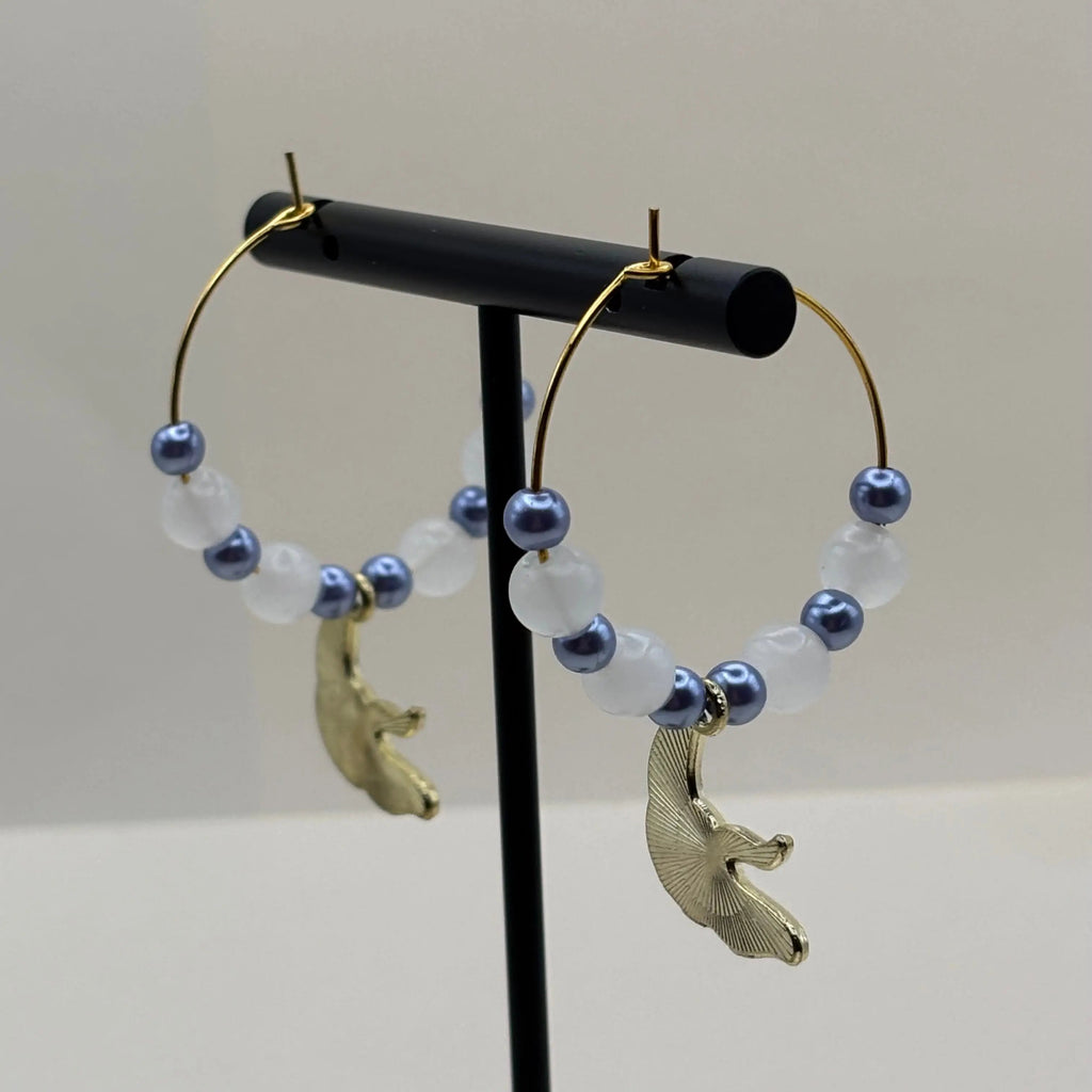 Une paire de boucles d'oreilles créoles dorées avec breloque raie 