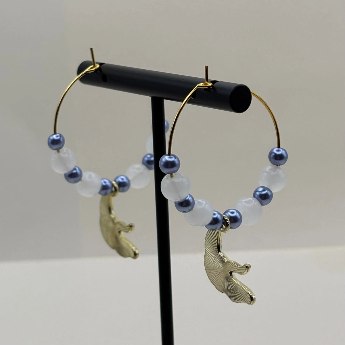 Une paire de boucles d'oreilles créoles dorées avec breloque raie 