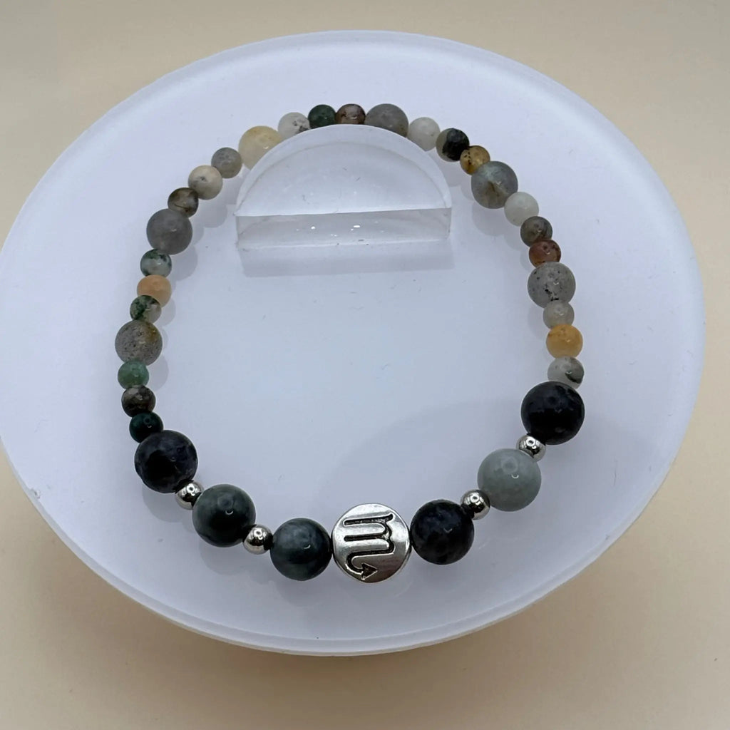 Bracelet aux perles multicolores dans des tons verts, gris et beige avec un médaillon argenté gravé au centre