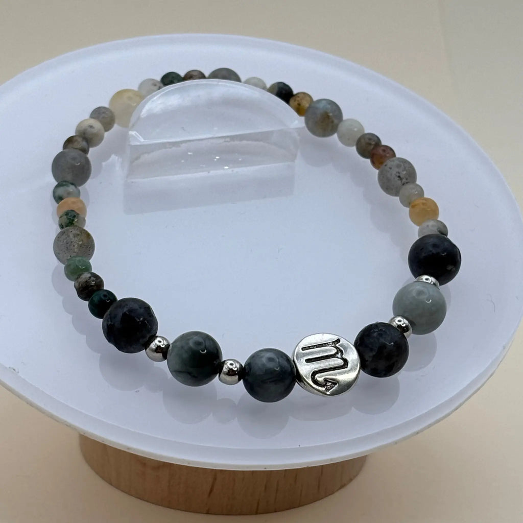 Bracelet aux perles variées gris, vert et beige décoré d’un médaillon argenté gravé positionné à l’avant
