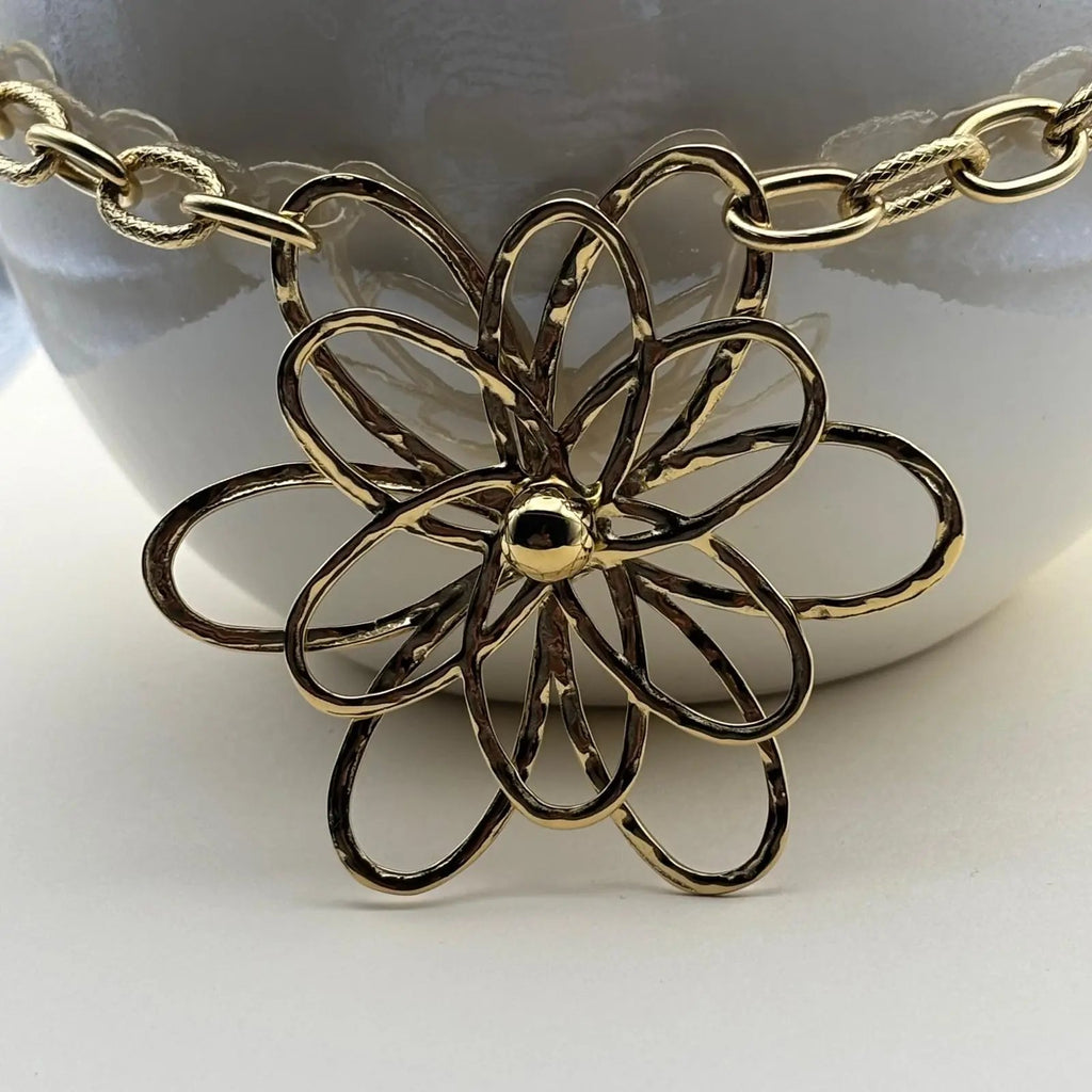 Un collier doré avec chaine grands maillons et pendentif en forme de fleur en acier inoxydable 