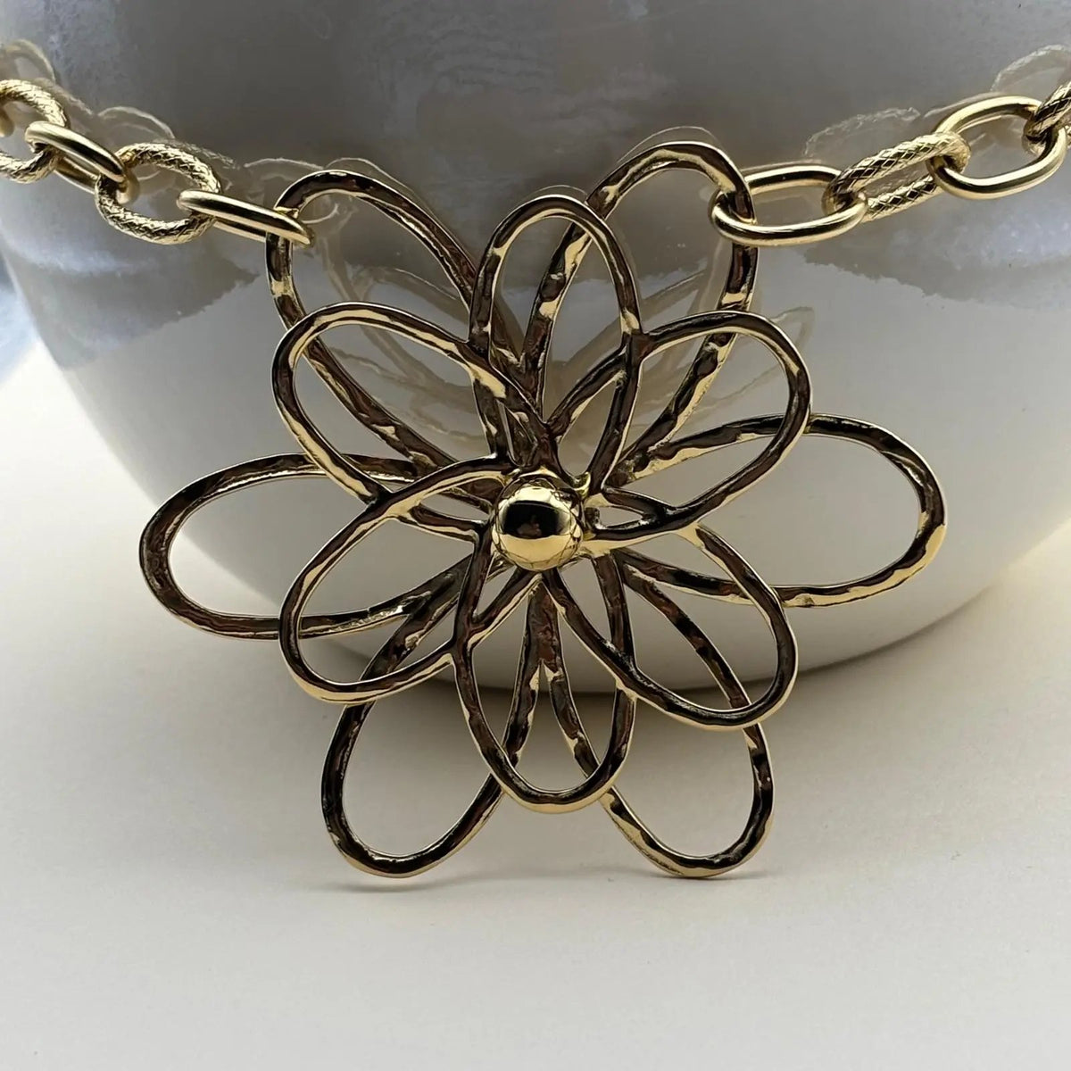 Un collier doré avec chaine grands maillons et pendentif en forme de fleur en acier inoxydable 