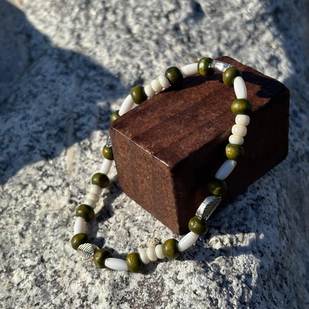 Vue de près d'un bracelet en perles artisanal avec des perles feuilles argentées et en bois sur élastique