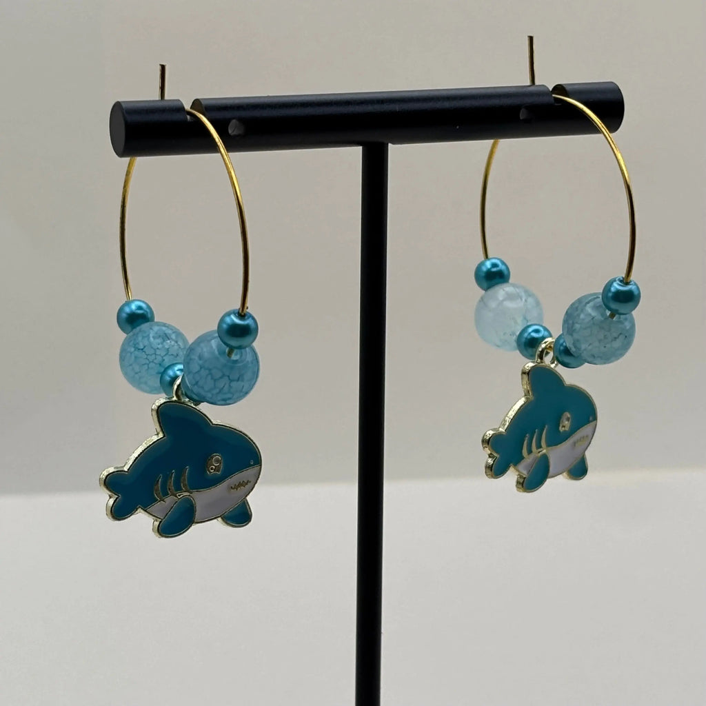 Des boucles d'oreilles créoles dorées avec perles bleues clair et breloque baleine bleu et blanche 