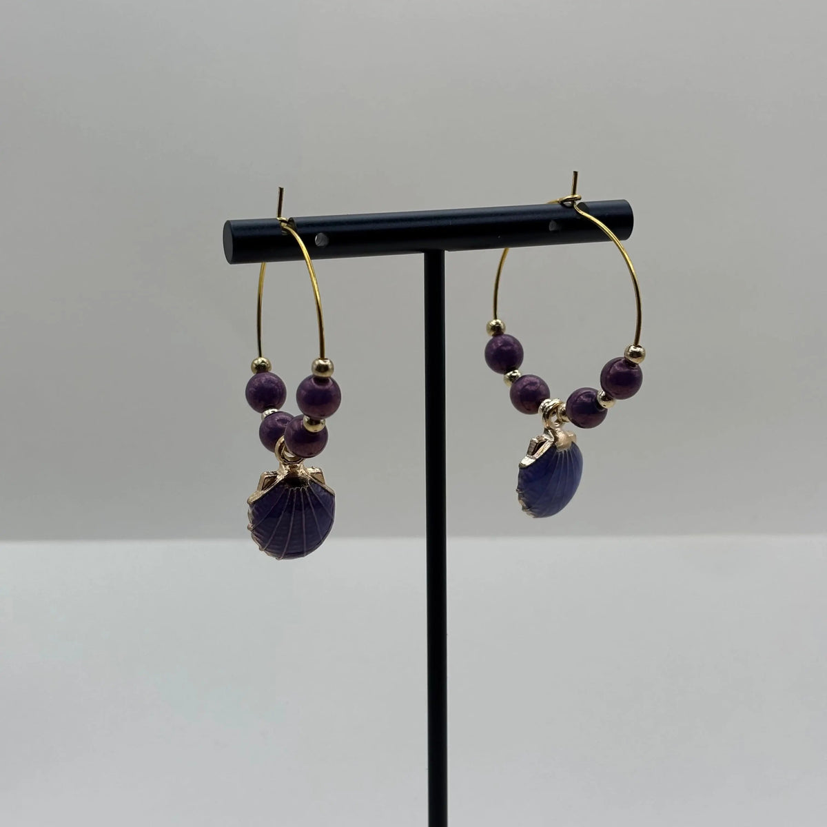Boucles d'oreilles créoles dorées avec perles violettes et breloque en forme de coquillage