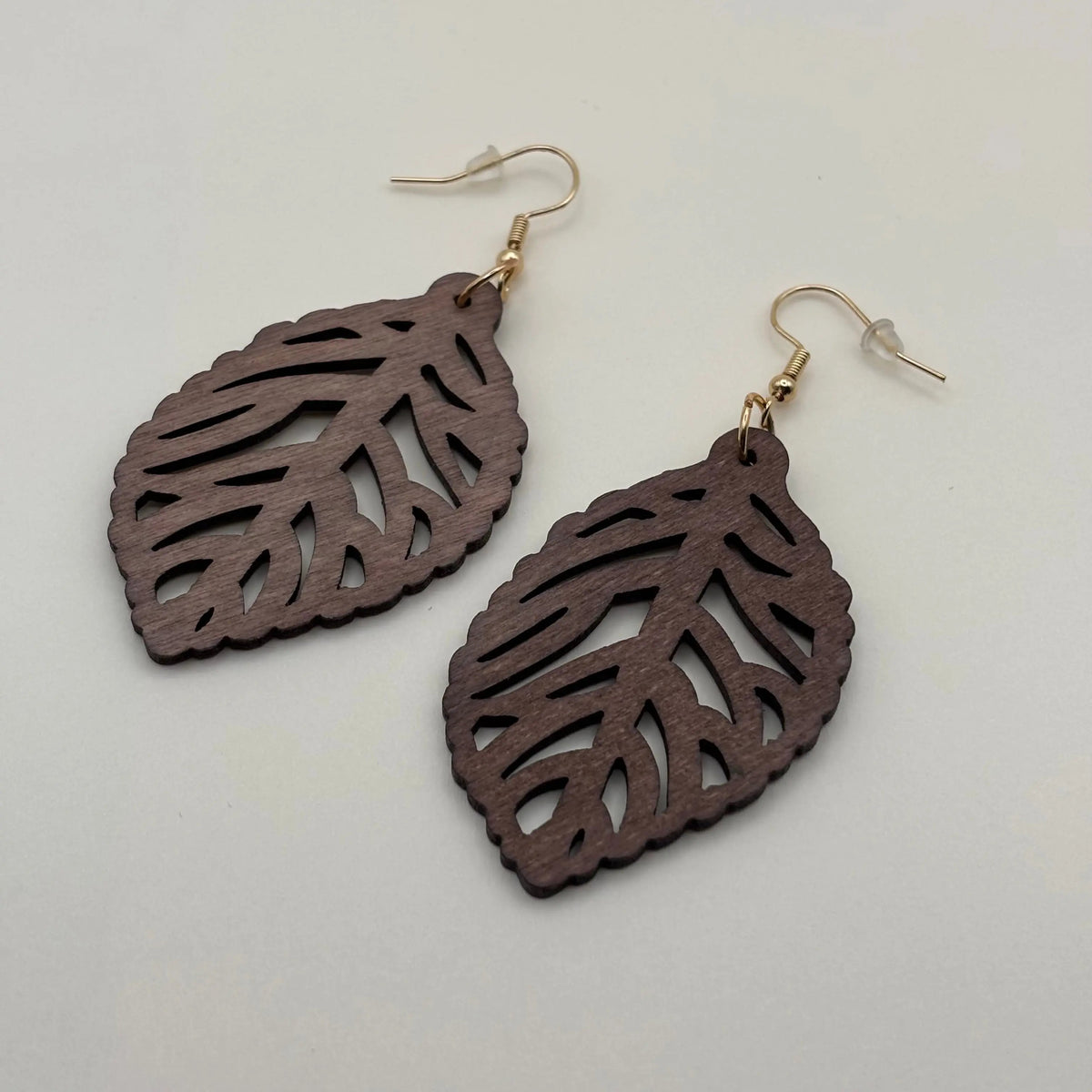Une paire de boucles d'oreilles fantaisie attache dorée avec boucle en bois motif de feuille