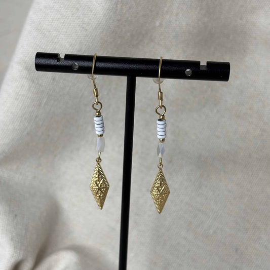 Boucles d'oreilles pendentif dorées avec perles plates blanches et breloque dorée rose des vents vendu sur le site internet prêtes à briller