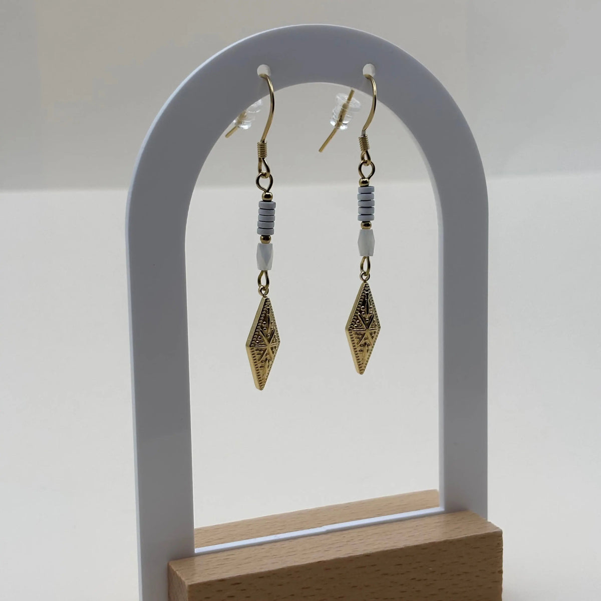 Boucles d'oreilles pendentif dorées avec perles plates blanches et breloque dorée rose des vents