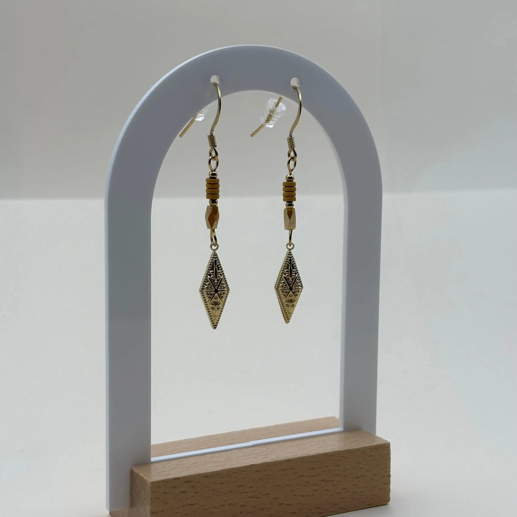 Des boucles d'oreilles pendentif dorées avec perles plates oranges et breloque dorée rose des vents