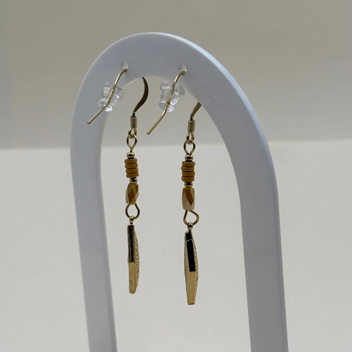 Une paire de boucles d'oreilles pendentif dorées avec perles plates oranges et breloque dorée rose des vents