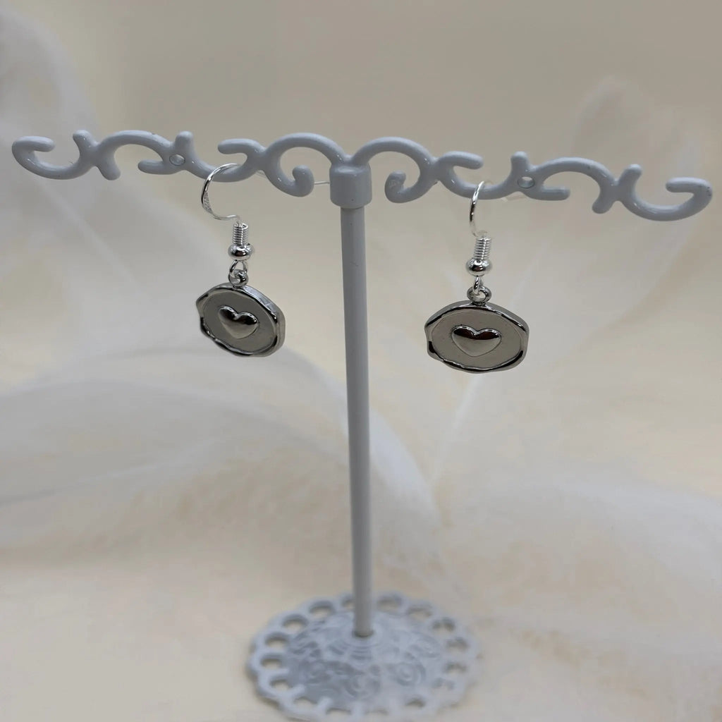 Paire de boucles d'oreilles argentées avec un coeur dans un pendentif