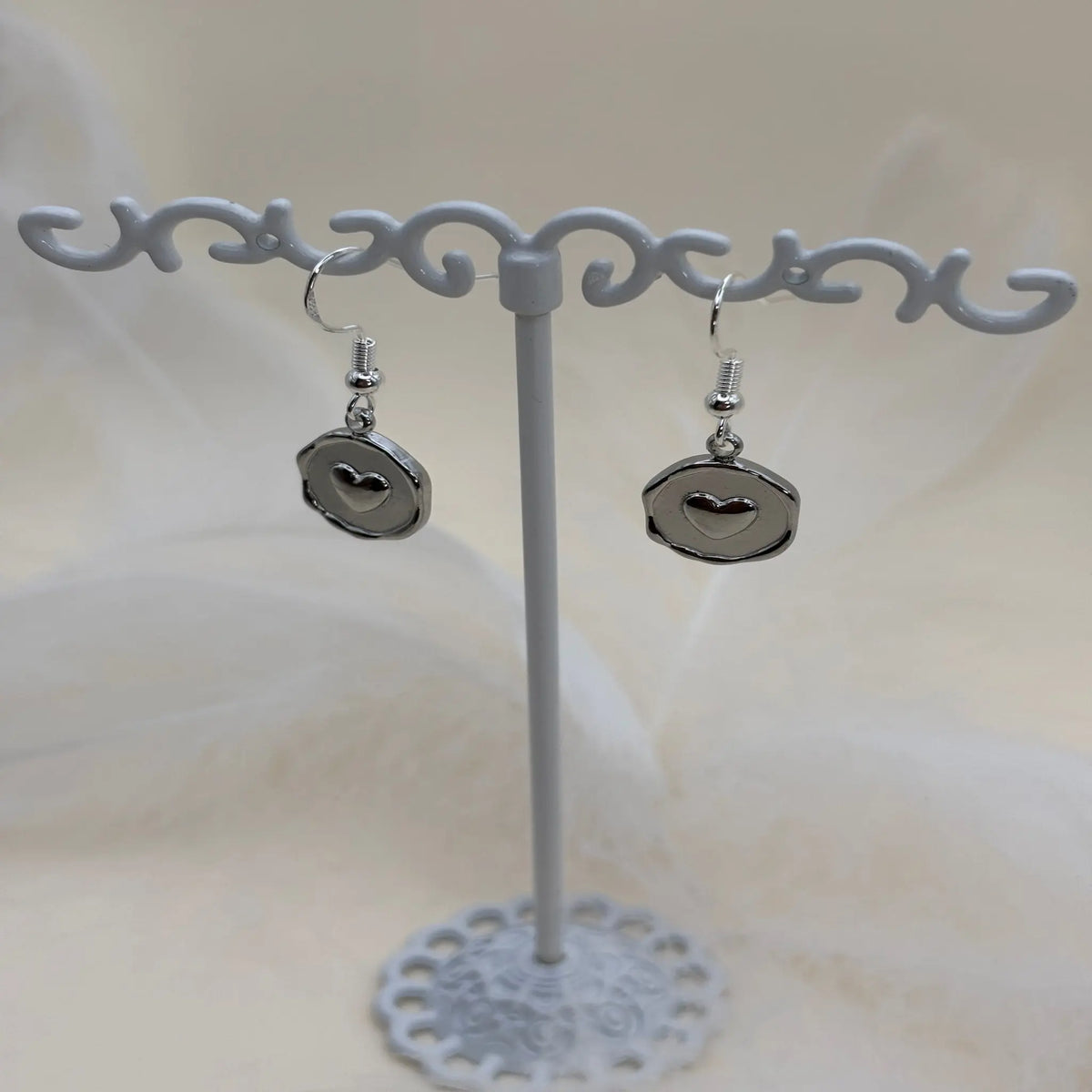 Paire de boucles d'oreilles argentées avec un coeur dans un pendentif