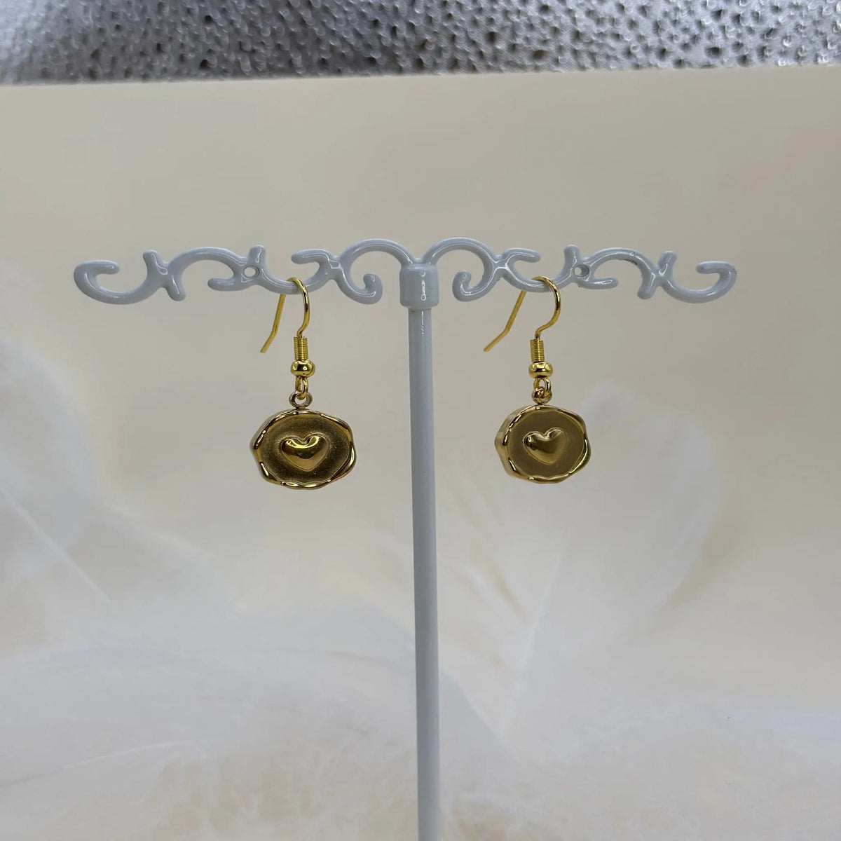 Paire de boucles d'oreilles dorées avec un coeur dans un pendentif