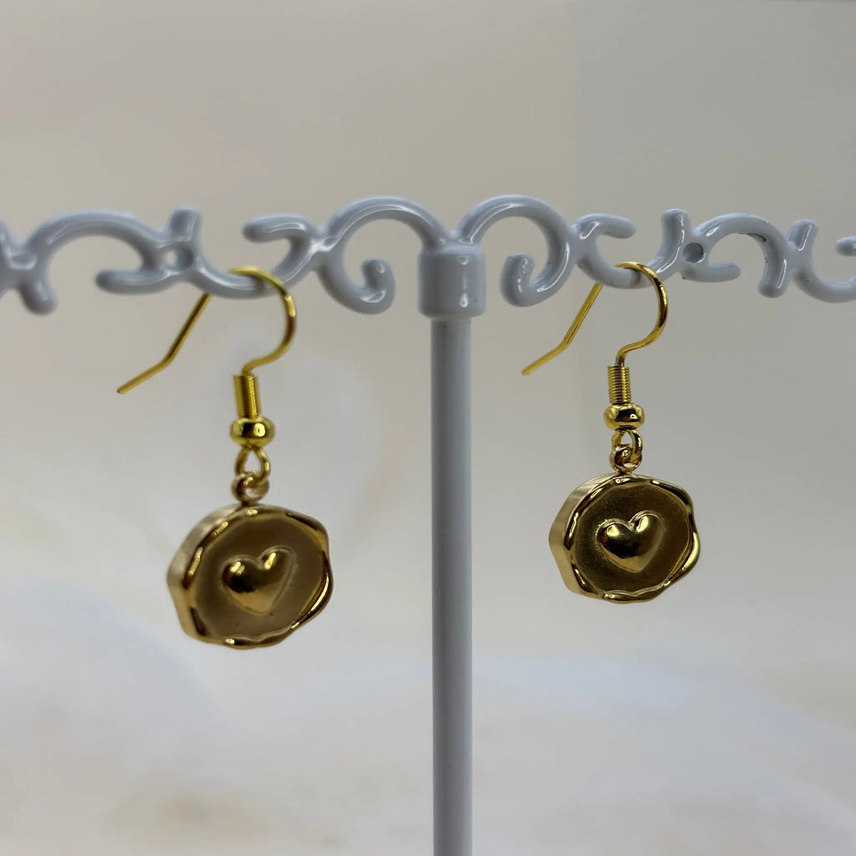 Une paire de boucles d'oreilles dorées avec un coeur dans un pendentif