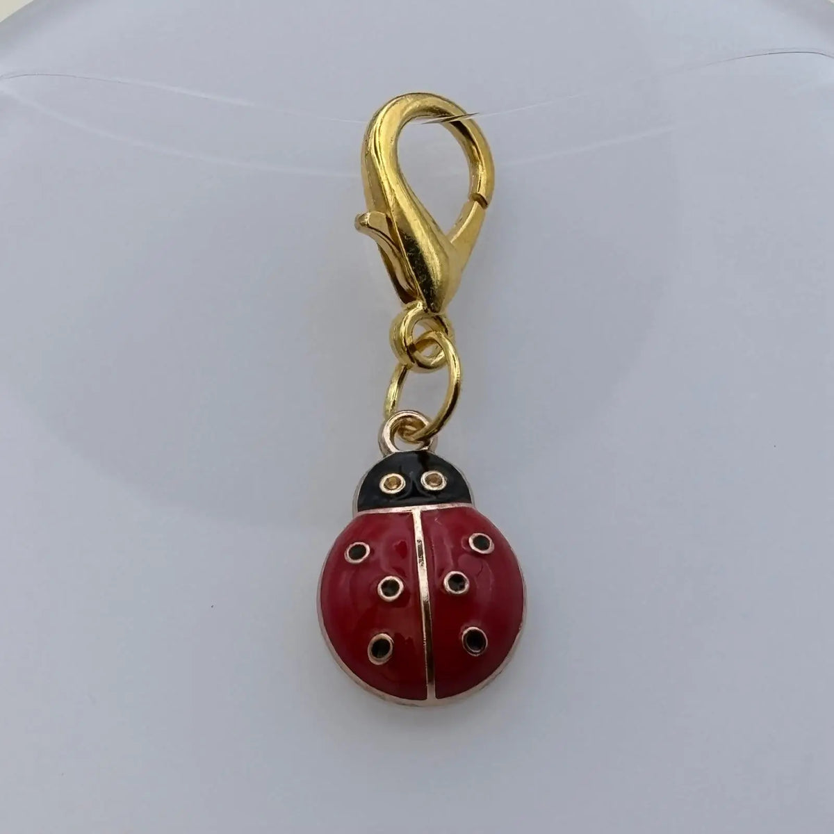 Bijou à accrocher doré avec breloque coccinelle rouge à pois noir