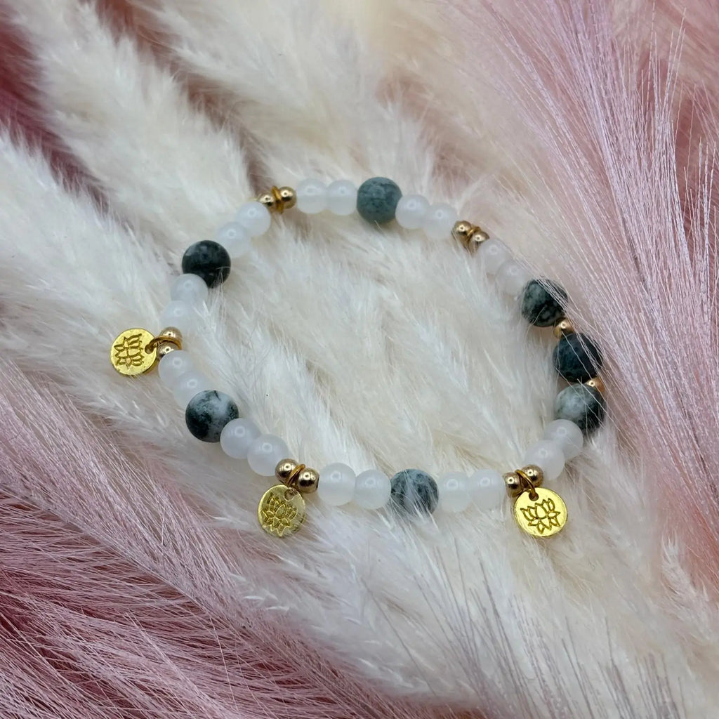 Vue de près d'un bracelet en perles artisanal avec breloques fleur de lotus et perles naturelles marbrées vertes 
sur élastique 