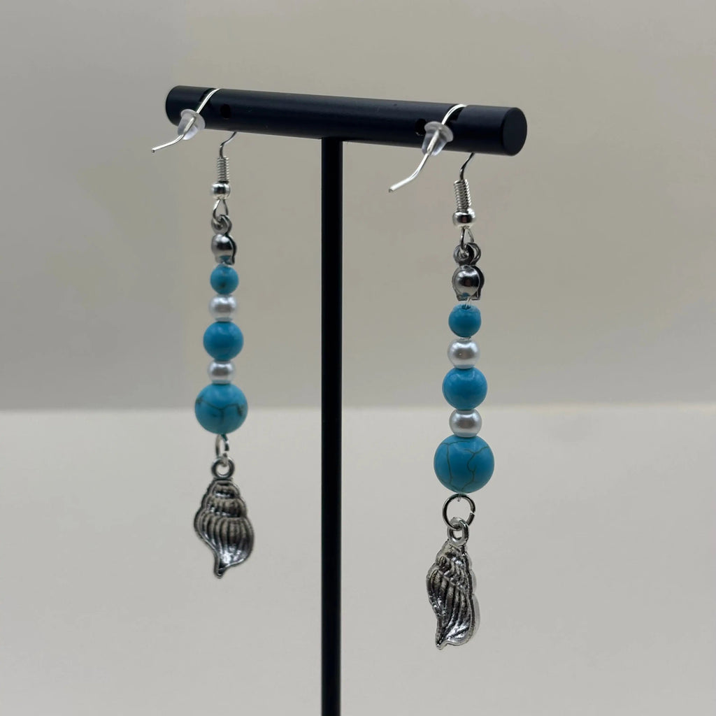 Des boucles d'oreilles argentées avec breloque coquillage et perles bleues