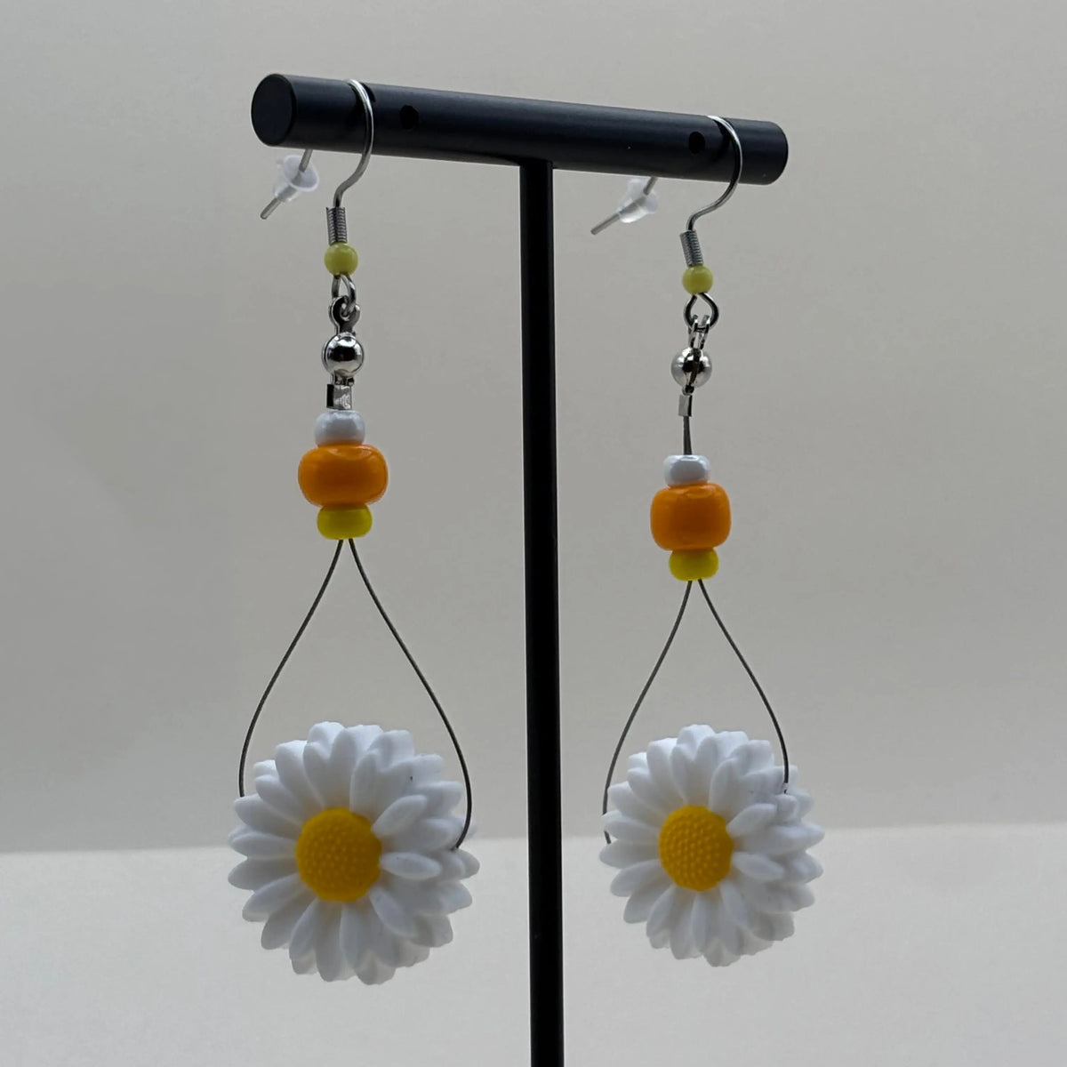 Des boucles d'oreilles artisanales créoles avec perles oranges jaune et blanche et fleur de marguerite 