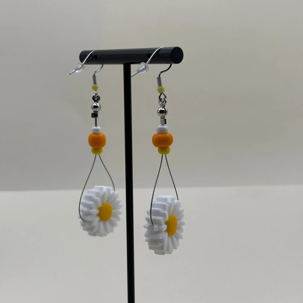 Une paire de boucles d'oreilles artisanales créoles avec perles oranges jaune et blanche et fleur de marguerite 