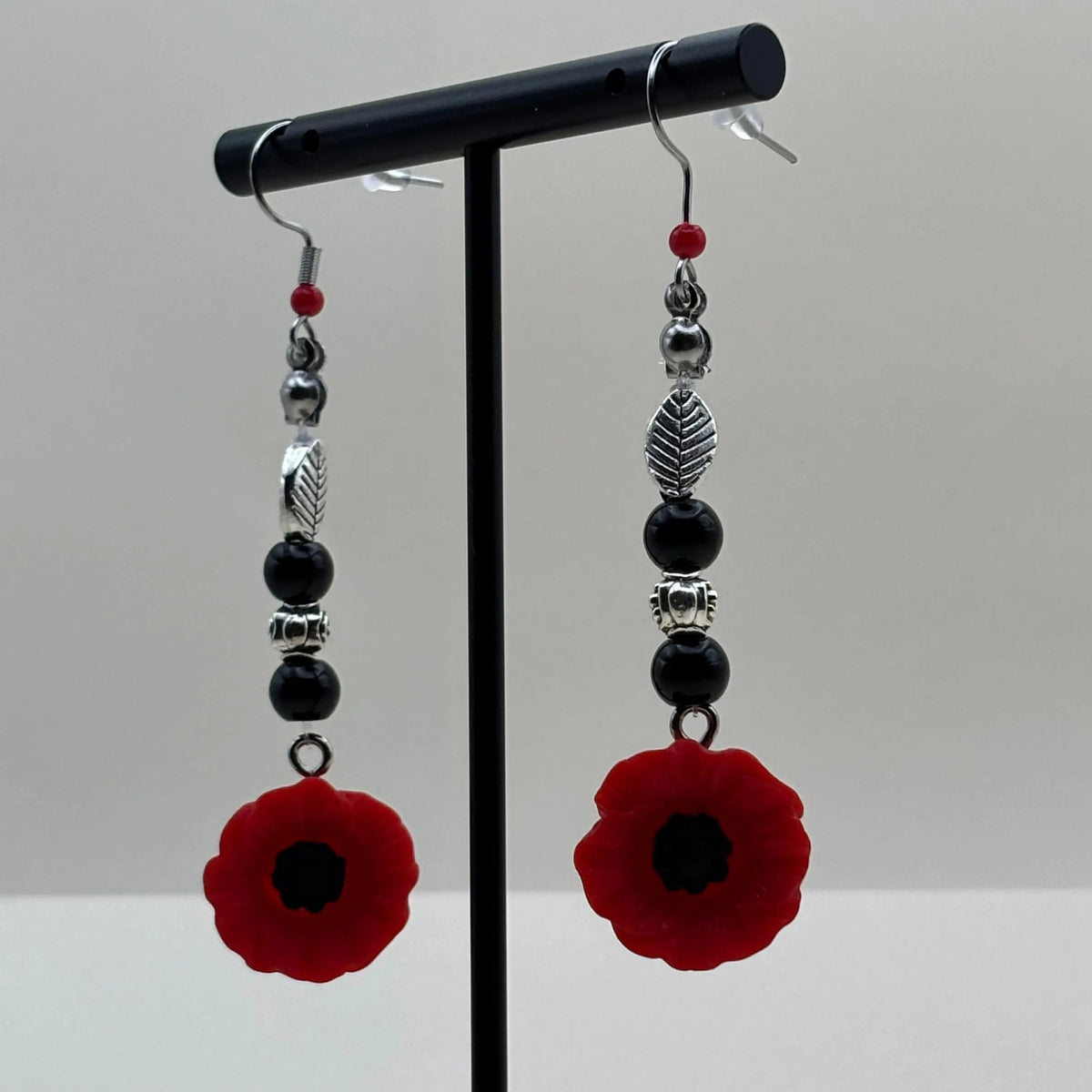 Des boucles d'oreilles argentées avec breloque fleur rouge et perles noires 