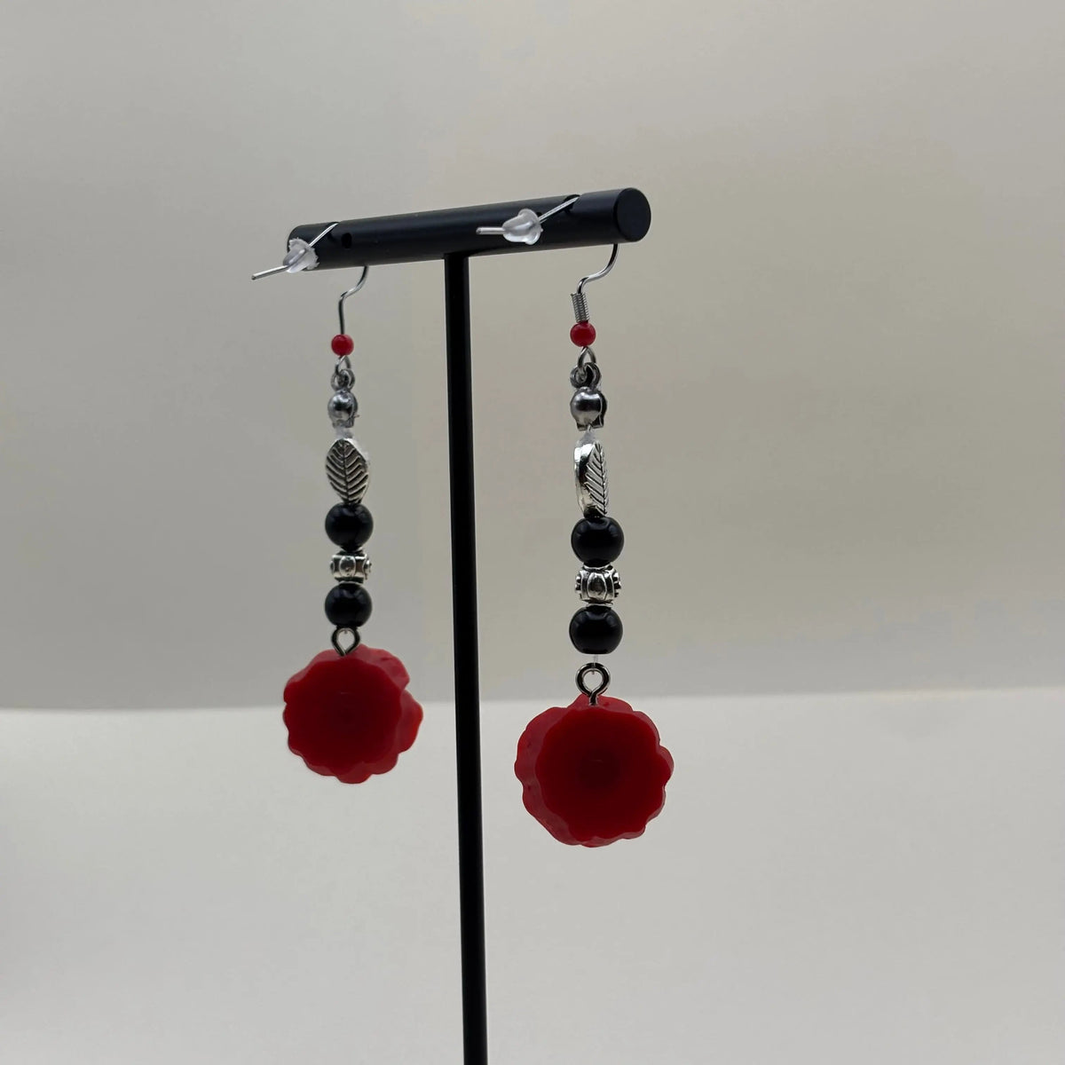 Une paire de boucles d'oreilles argentées avec breloque fleur rouge et perles noires 