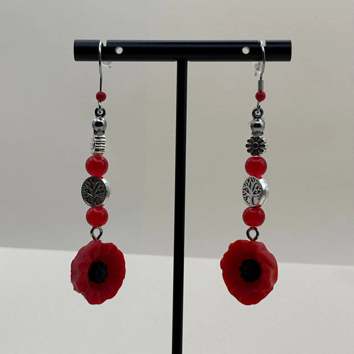 Des boucles d'oreilles argentées avec breloque fleur rouge et perles rouges 