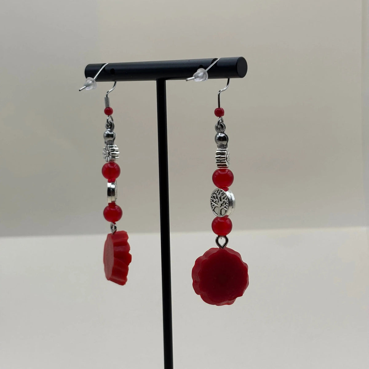 Une paire de boucles d'oreilles argentées avec breloque fleur rouge et perles rouges 