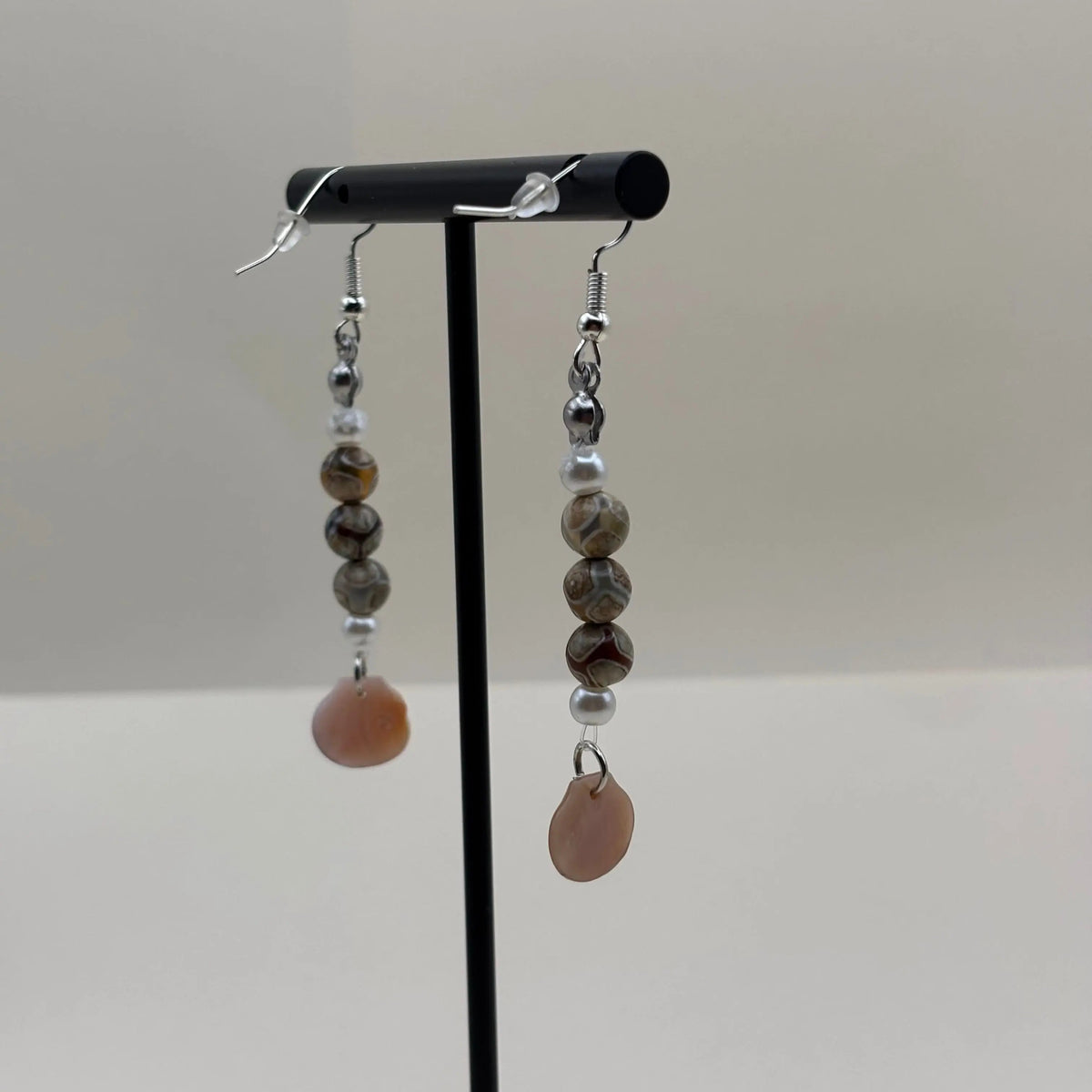 Des boucles d’oreilles pendantes avec attache argentée et breloque en forme de coquillage nacré et perles colorées marbrées