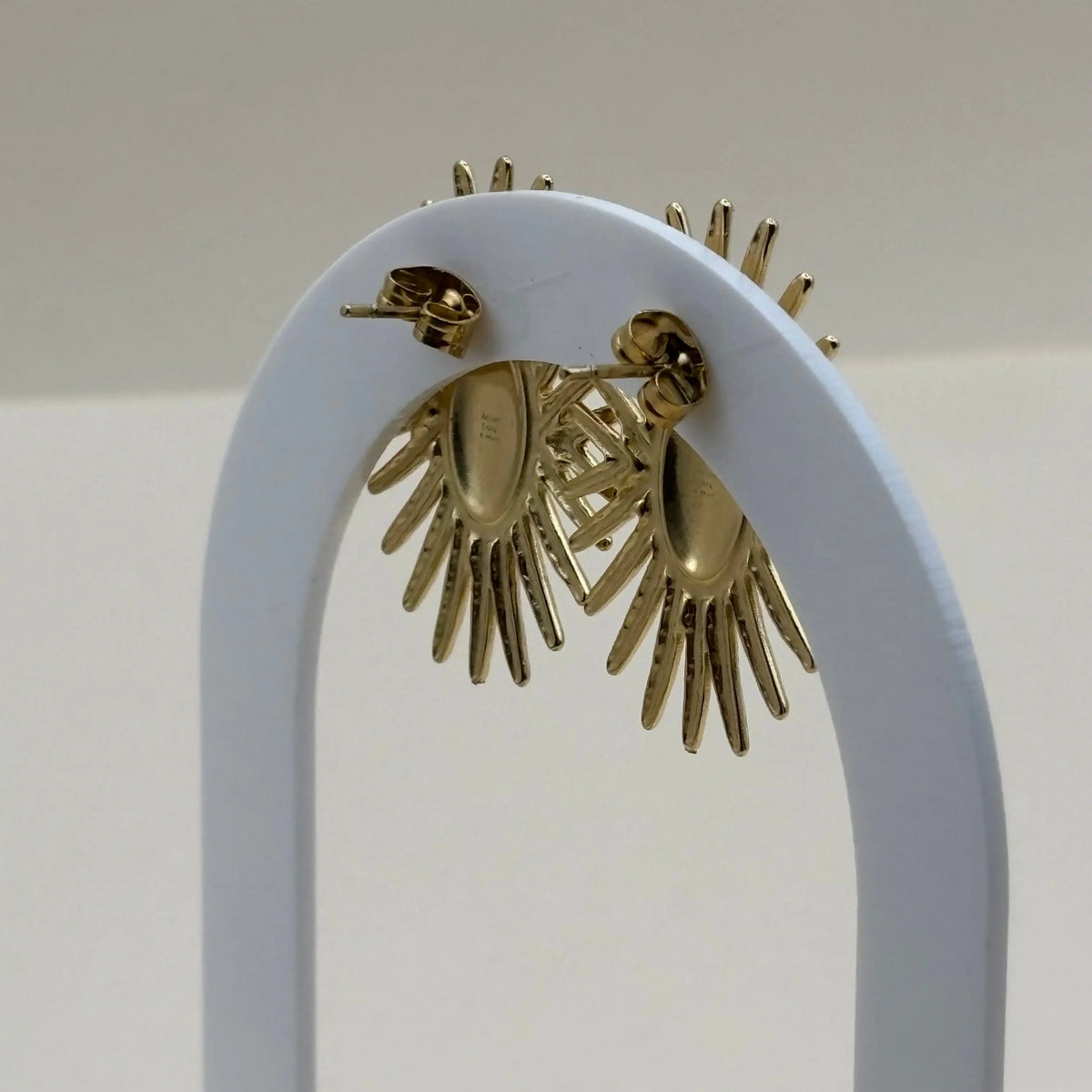 Une paire de boucles d'oreilles dorées motif soleil doré en acier inoxydable