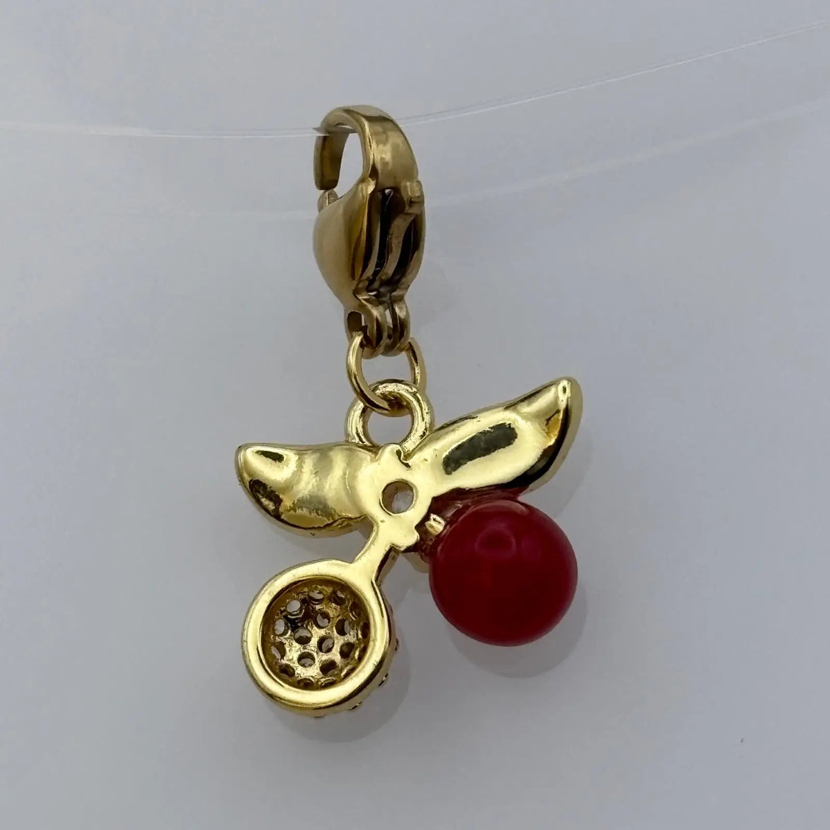 Bijou à accrocher de couleur dorée avec breloque feuille dorée perles et strass et pastille rouge