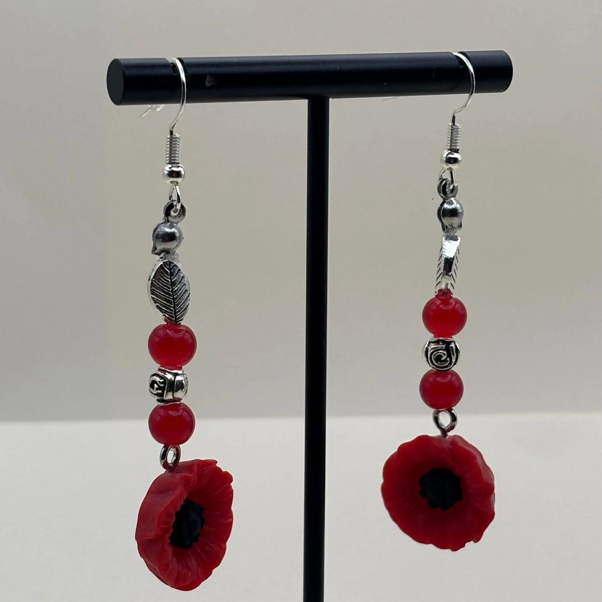 Des boucles d’oreilles pendantes avec attache argentée  breloque fleur rouge et perles rouges et plumes argentées 