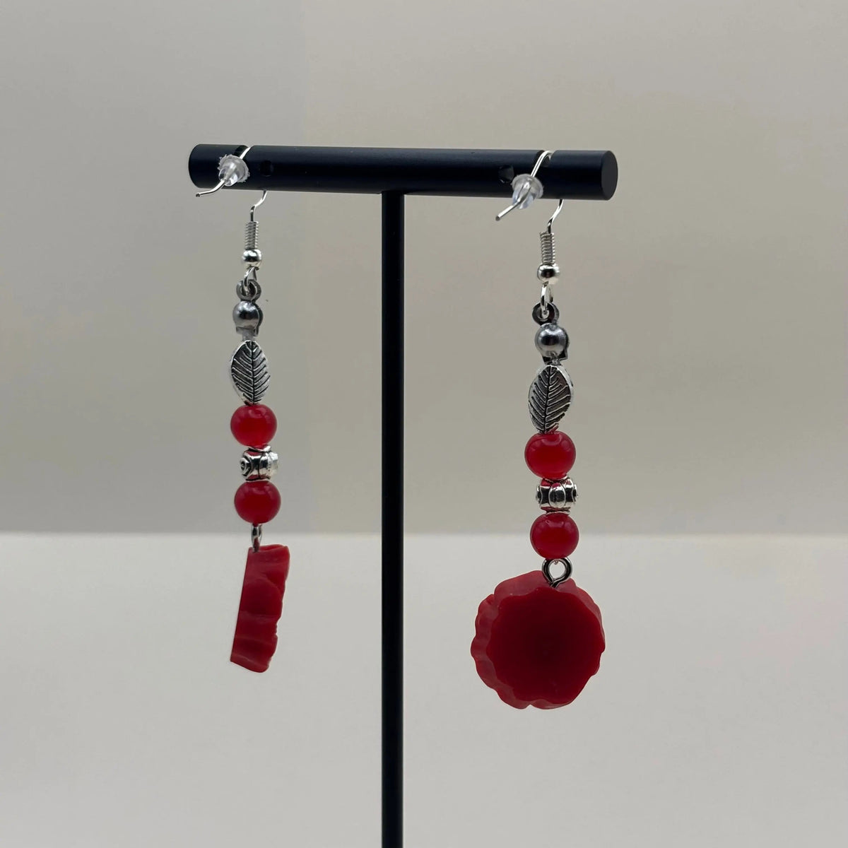 Une paire de boucles d’oreilles pendantes avec attache argentée  breloque fleur rouge et perles rouges et plumes argentées 