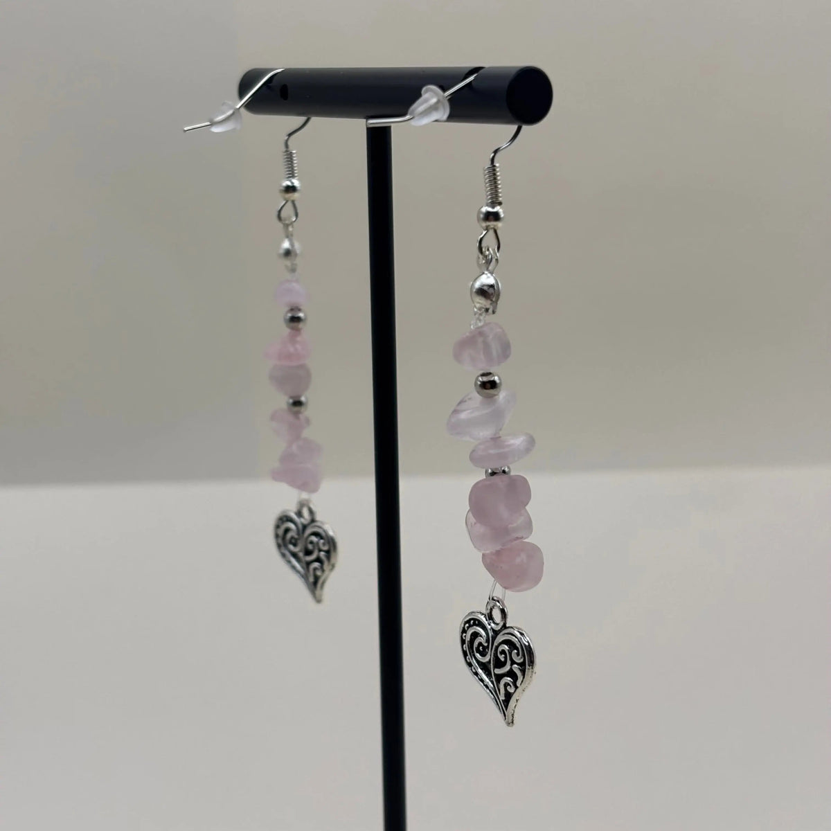 Des boucles d’oreilles pendantes avec attache argentée avec des perles violettes et une breloque en forme de coeur 