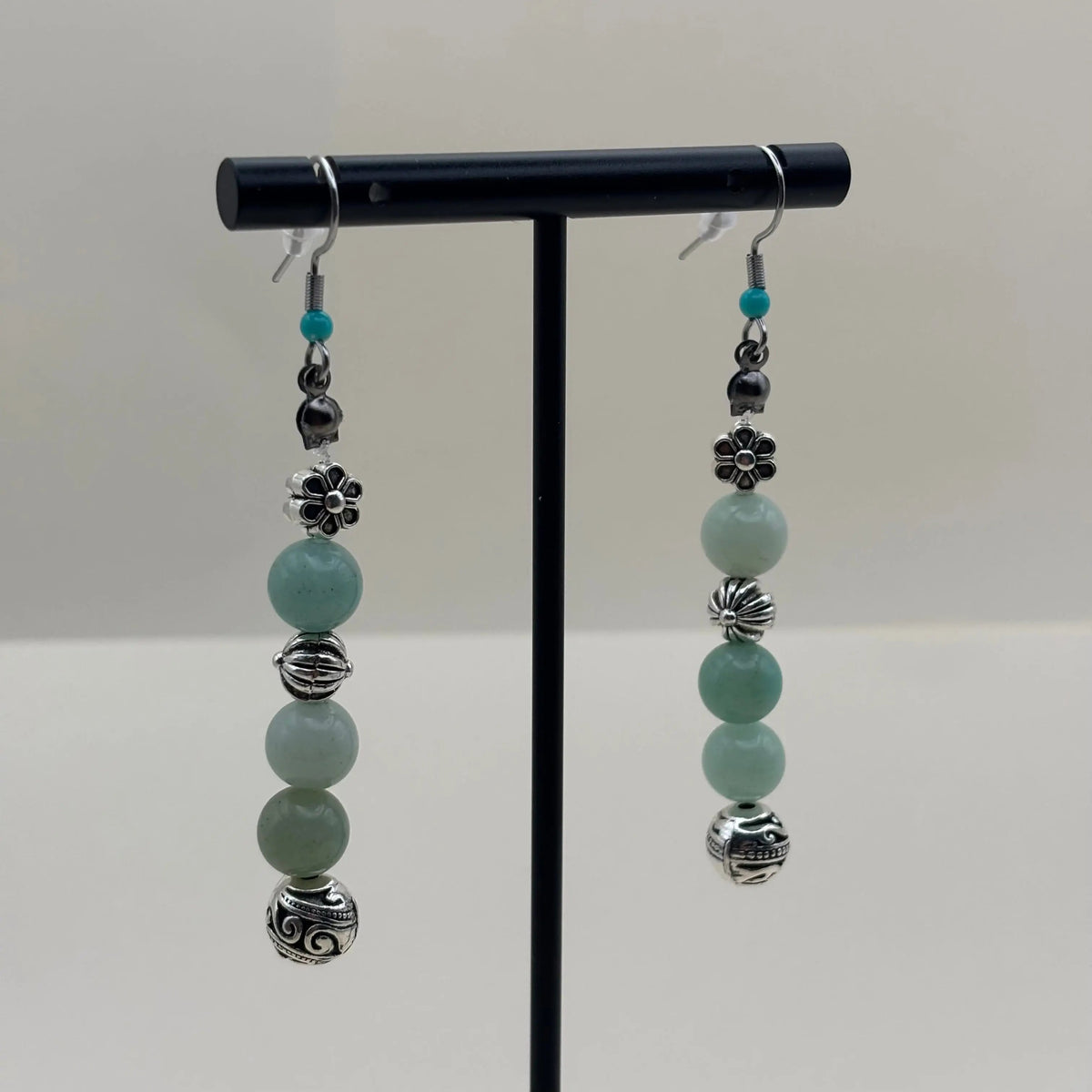 Des boucles d’oreilles pendantes avec attache argentée breloque en forme de sphère argentée et perles bleu vert 